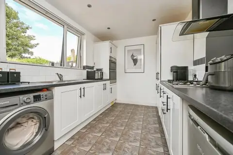 Fitted kitchen with white units, dark worktops and garden-facing window